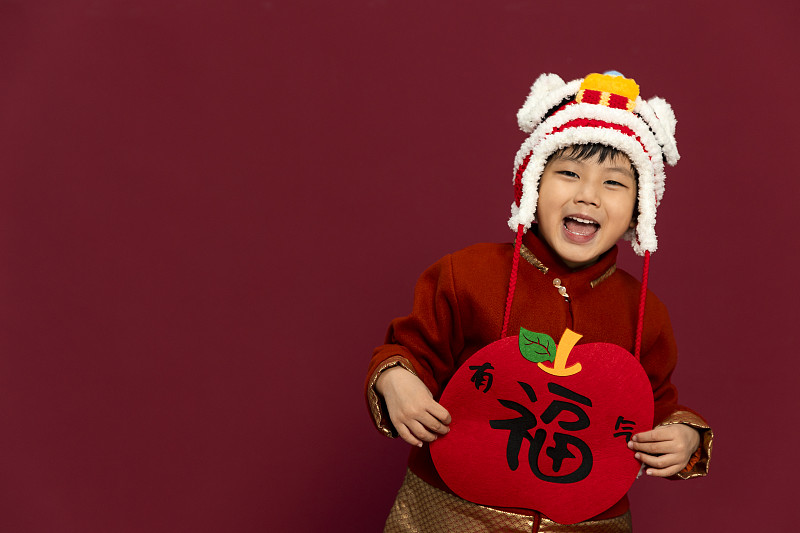 儿童庆祝春节系列：欢乐的小男孩拿着福字庆祝新春图片下载