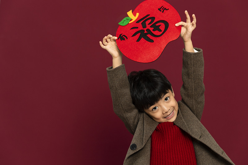 儿童庆祝春节系列：欢乐的小男孩拿着福字庆祝新春图片下载