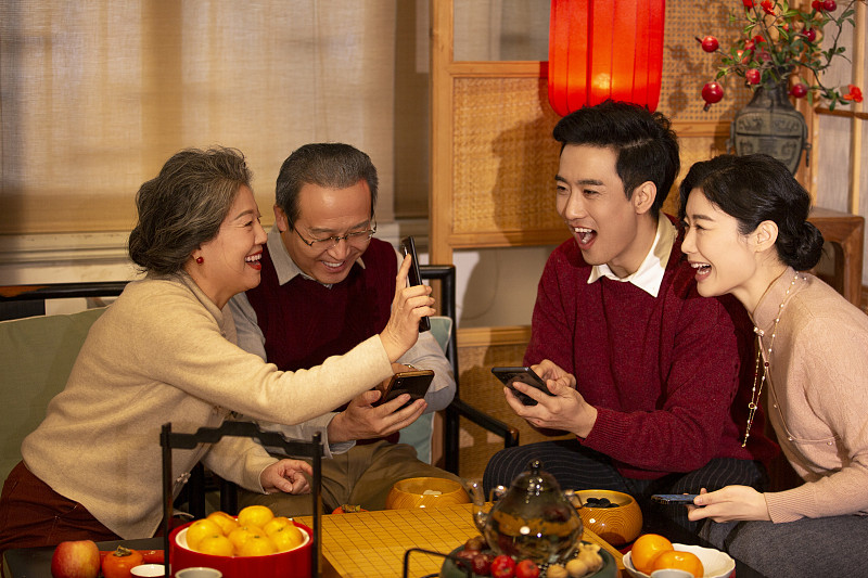 东方家庭过年：一家人在客厅用手机抢红包图片下载