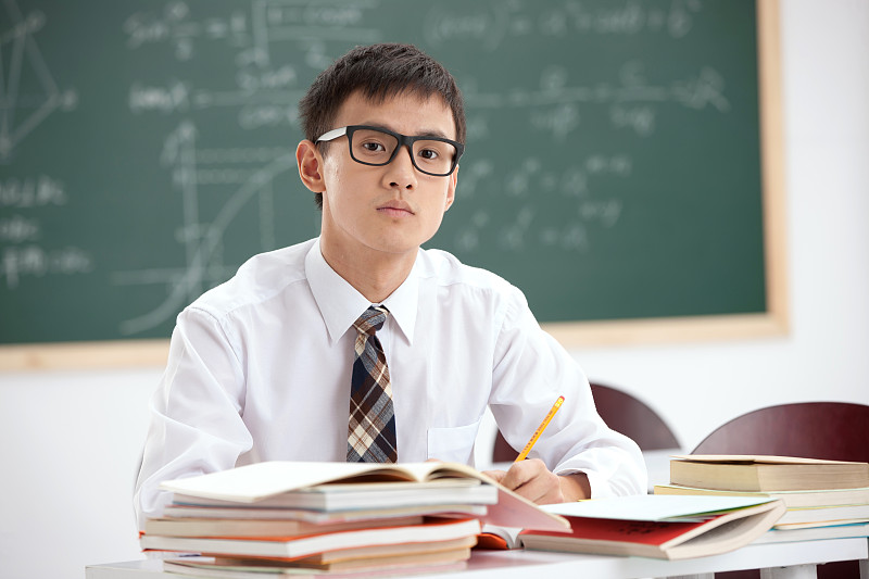一个戴着眼镜的中学男生坐在教室里图片下载