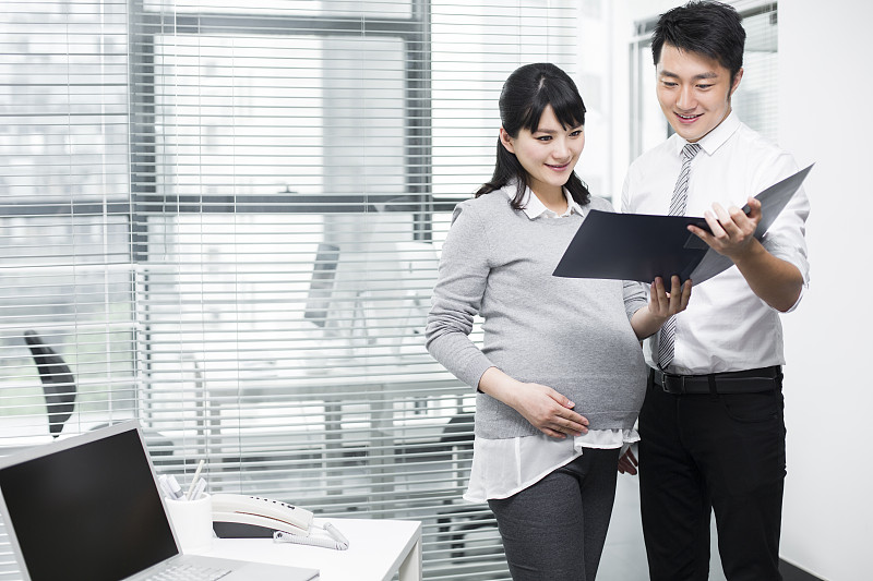 怀孕的商务女士和同事一起工作图片下载