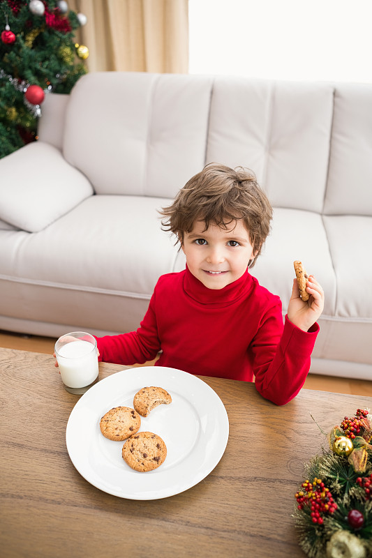 欢乐的小男孩在客厅里喝着牛奶和吃着饼干图片下载