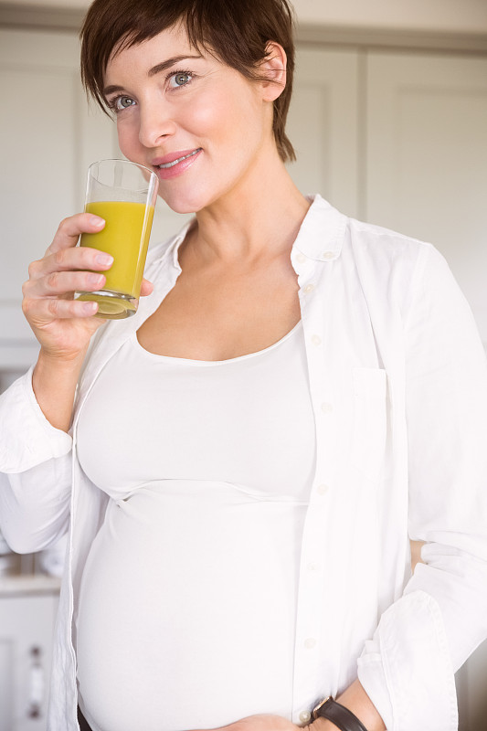 孕妇在家厨房里喝着橙汁图片下载