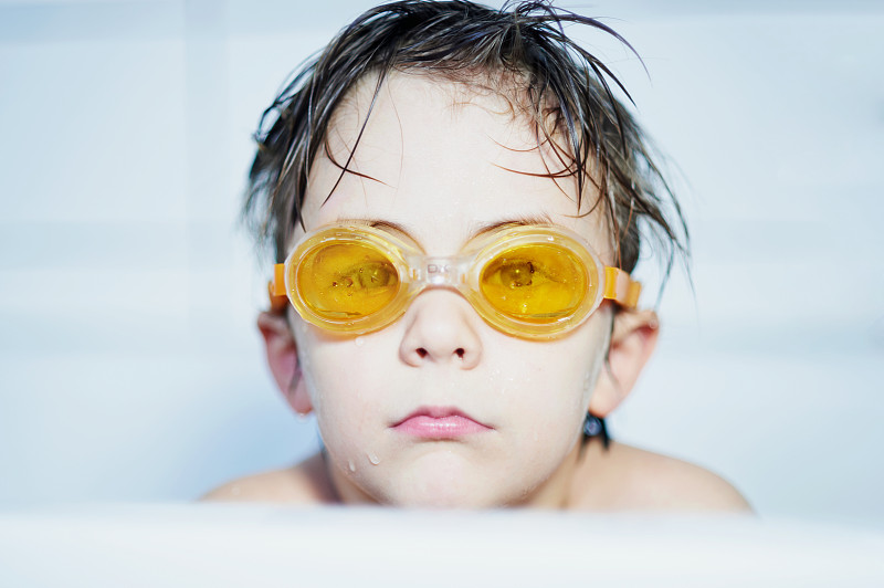 男孩的肖像(8-9)坐在浴缸与黄色泳镜图片下载