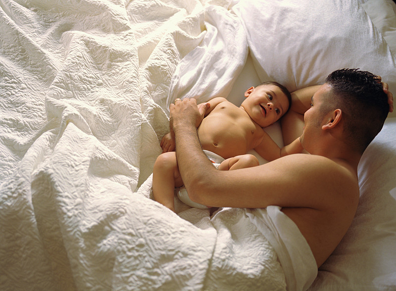 躺在床上的父亲和他的婴儿儿子图片素材