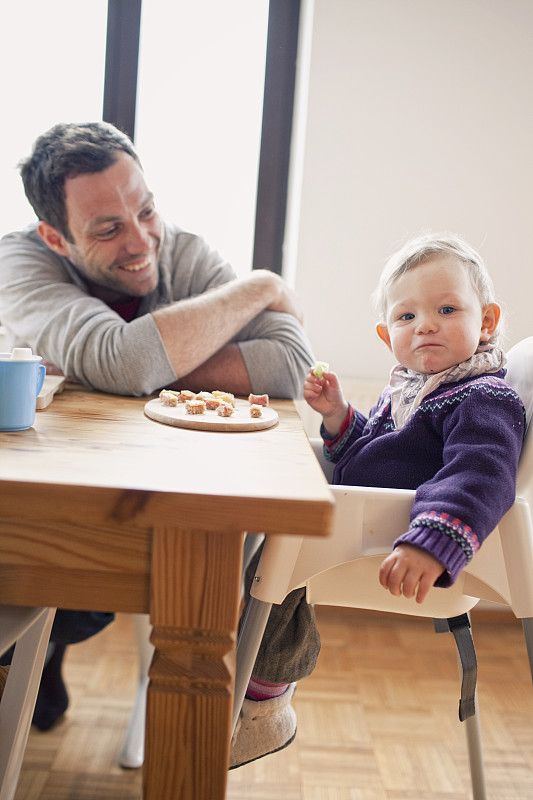 父亲和女儿(6-12个月)坐在餐桌旁图片素材