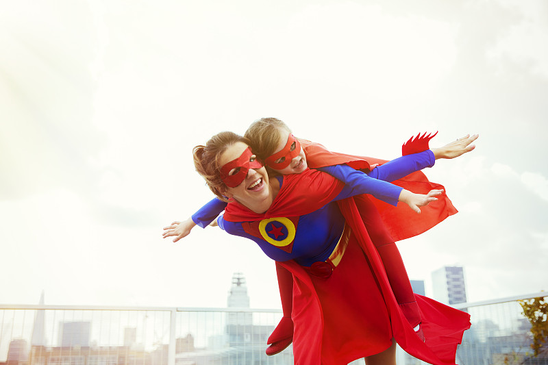 超级英雄妈妈和女儿在城市屋顶上玩耍图片下载
