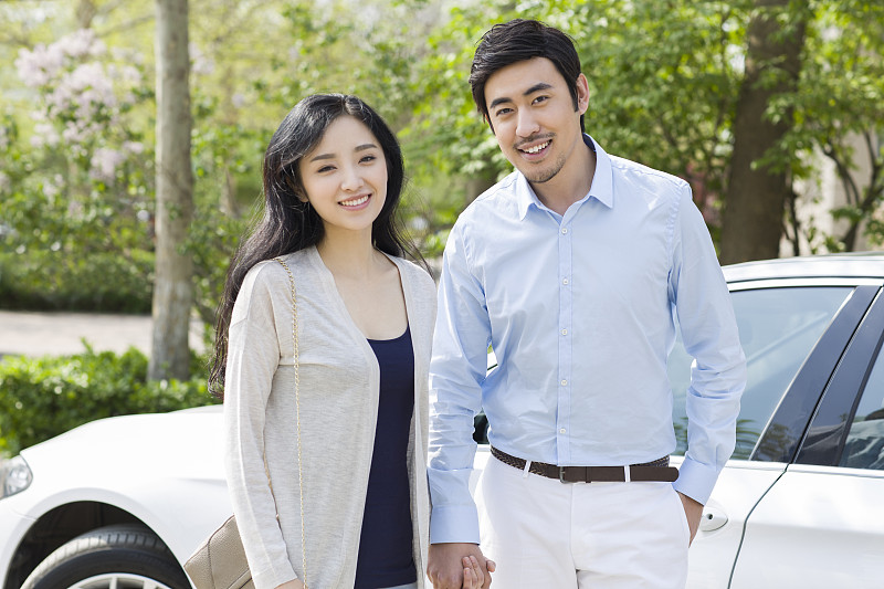 快乐的年轻夫妇站在汽车旁图片下载