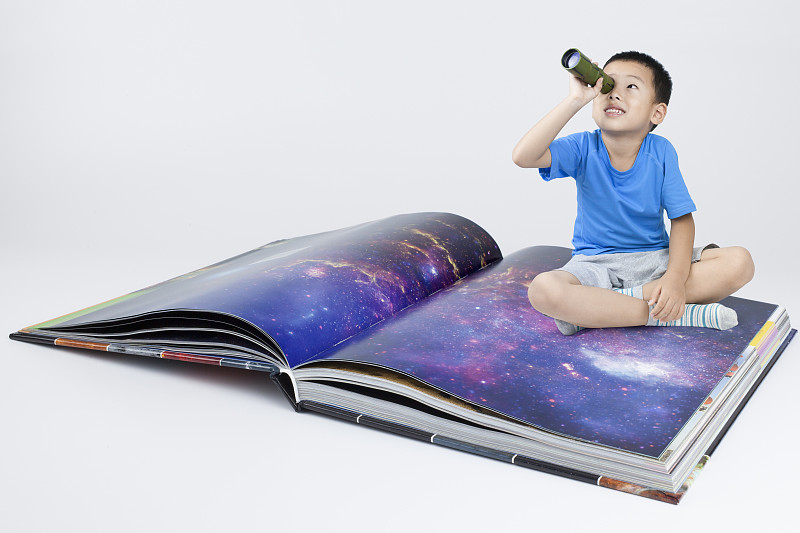 快乐的小男孩透过望远镜看天空图片素材