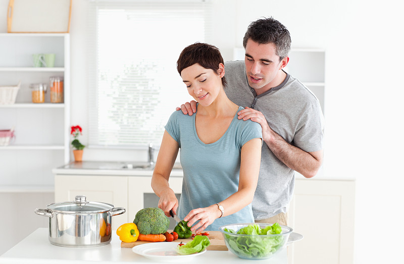 男人按摩他的妻子，而她正在厨房切蔬菜图片下载