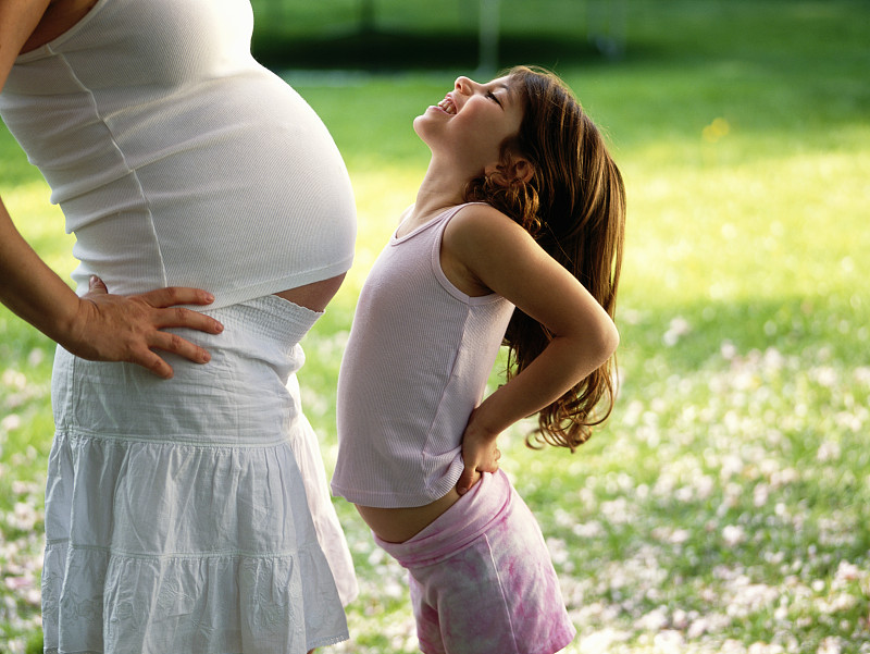 女孩(4-6)向孕妇腹部推，侧视图片下载