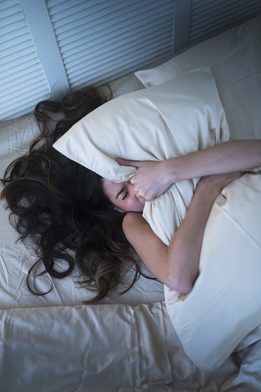 沮丧的西班牙妇女紧握着床上的枕头图片下载