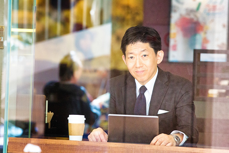 自信的日本求职者在咖啡馆用平板电脑抬头图片下载