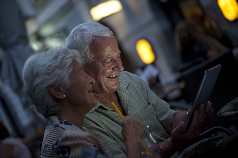 一对老年夫妇晚上在咖啡馆里用平板电脑图片下载