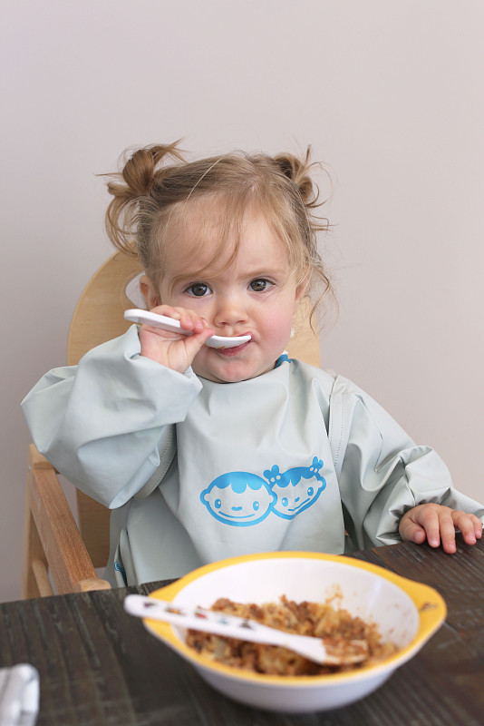 小女孩用勺子吃饭，肖像图片下载
