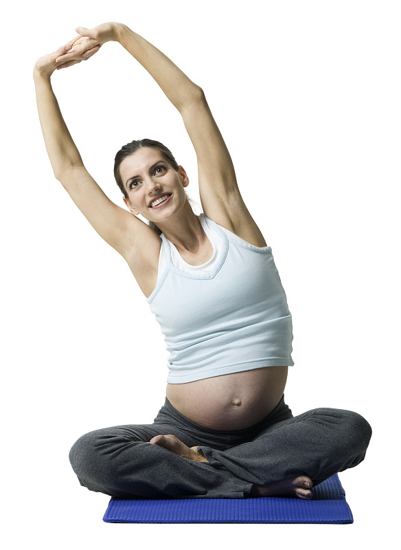 一个孕妇坐在地板上伸展身体的肖像图片下载