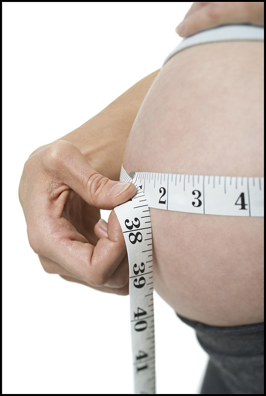 一个孕妇测量她的腹部的中段视图图片下载