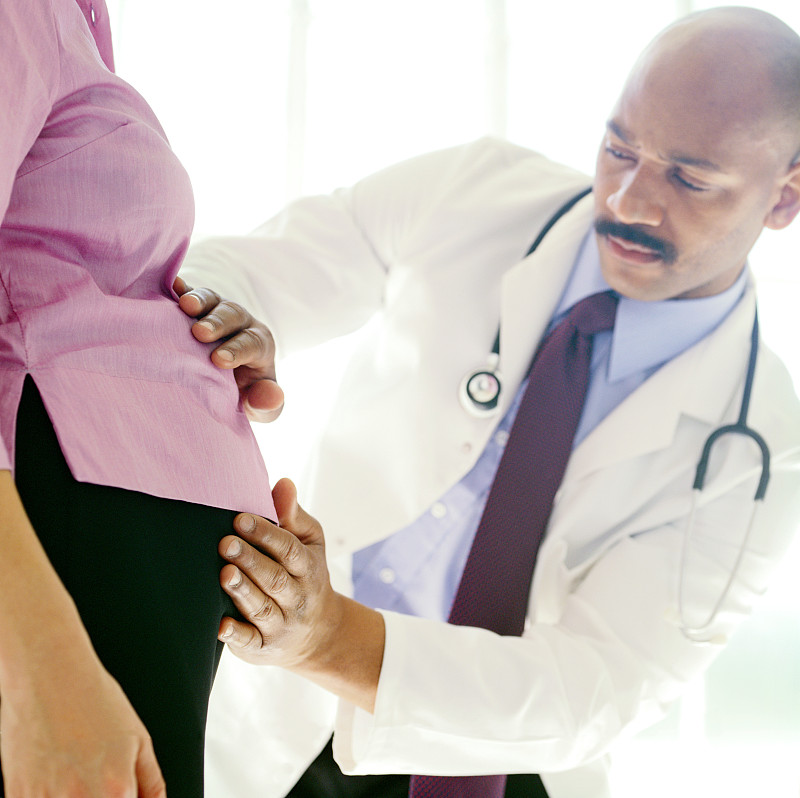 一个年轻男医生感觉孕妇的胃的肖像图片下载