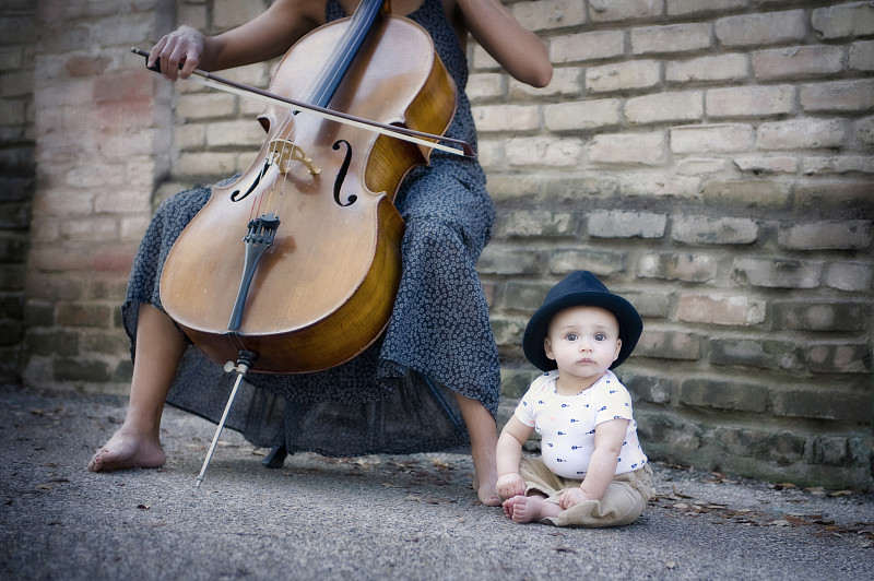 混血音乐家演奏大提琴与婴儿的女儿图片下载
