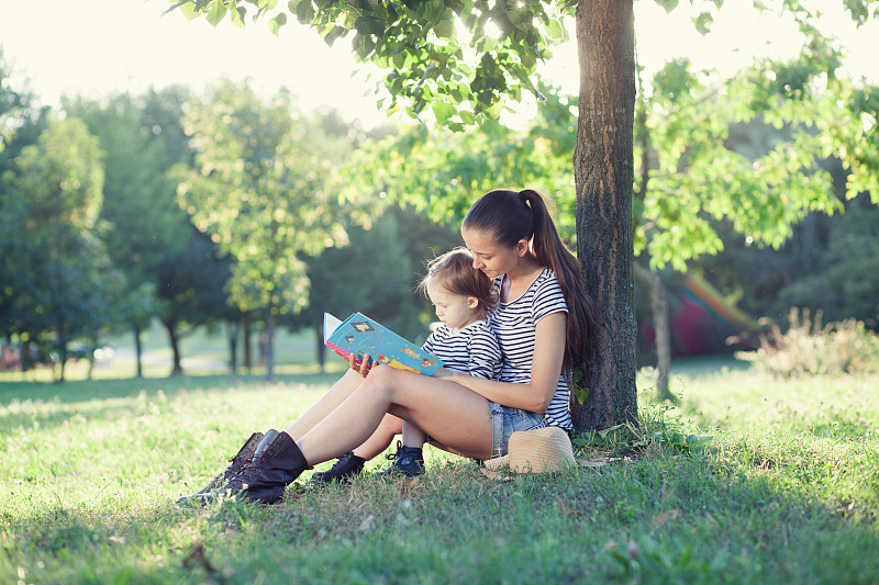 年轻时尚的母亲和蹒跚学步的孩子阅读书在g图片下载