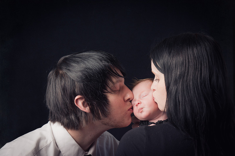 父母亲吻新生儿的脸颊图片下载