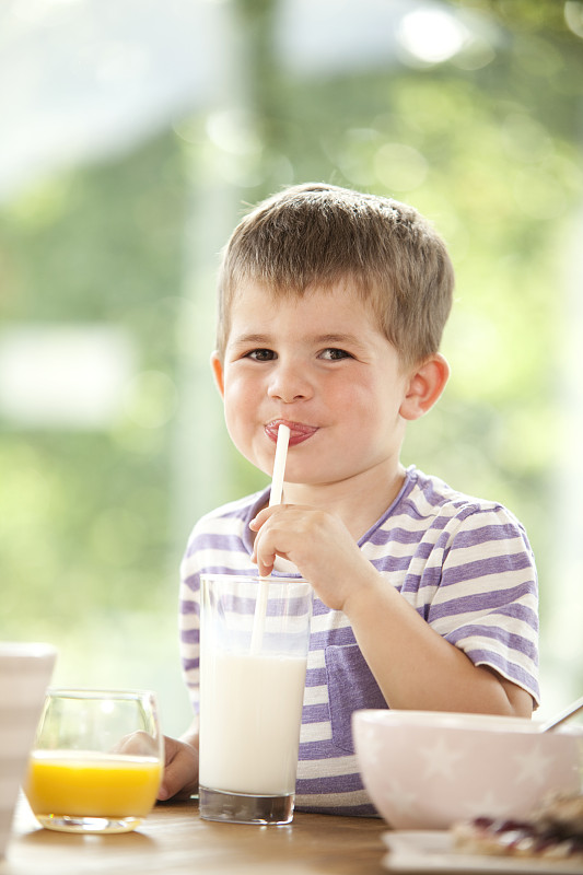 男孩用稻草喝牛奶的肖像图片下载