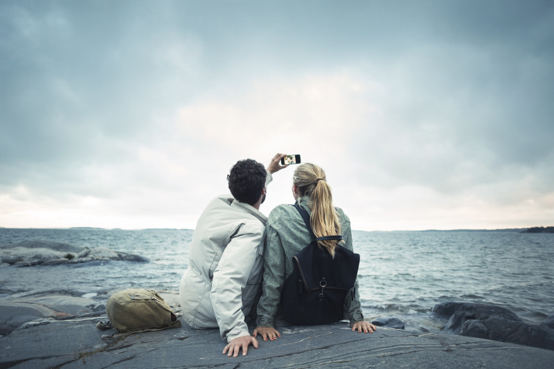 一对情侣坐在海边的岩石上自拍图片素材