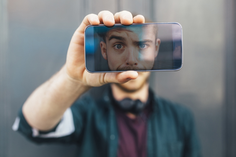 智能手机显示年轻人做鬼脸图片素材
