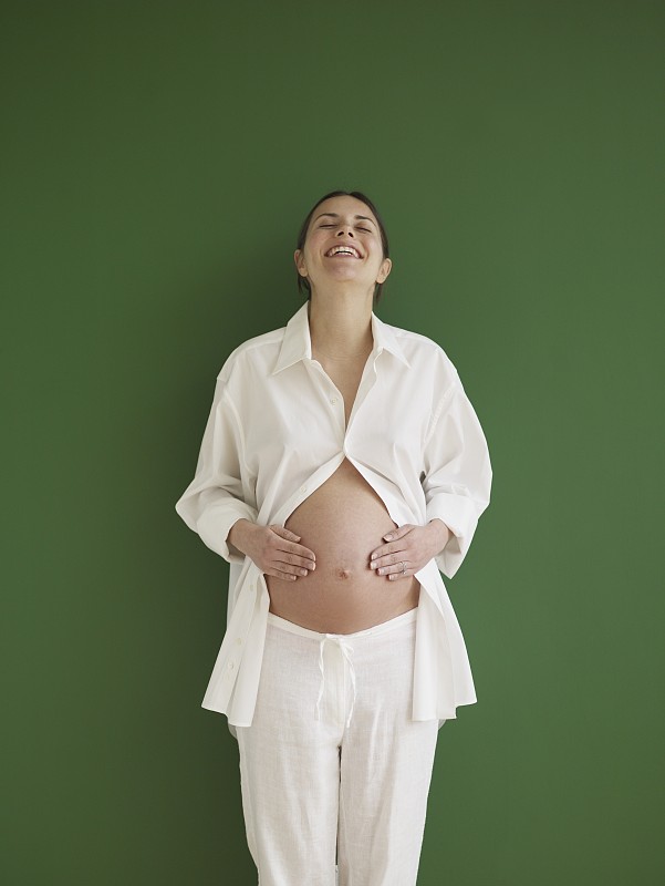 孕妇抱着裸露的腹部，微笑着图片下载