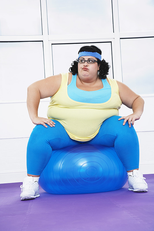 超重女子坐在健身球上图片下载