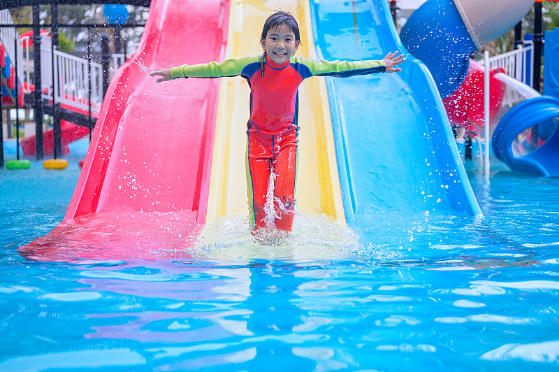 亚洲小孩小男孩玩和有乐趣滑滑梯在水上公园图片素材