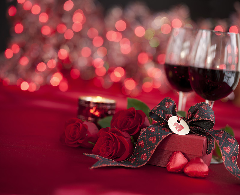 情人节红玫瑰和红酒与礼物在散焦灯光的背景图片素材