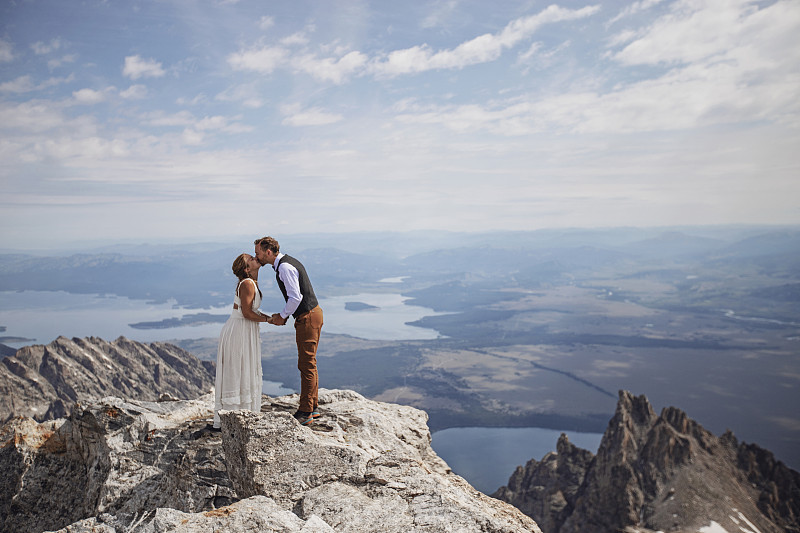 新郎和新娘在怀俄明州的山顶上接吻图片素材