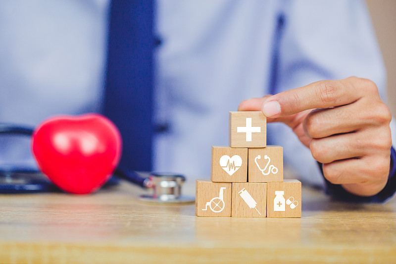 健康保险概念，手安排木块堆叠与图标医疗保健。图片素材