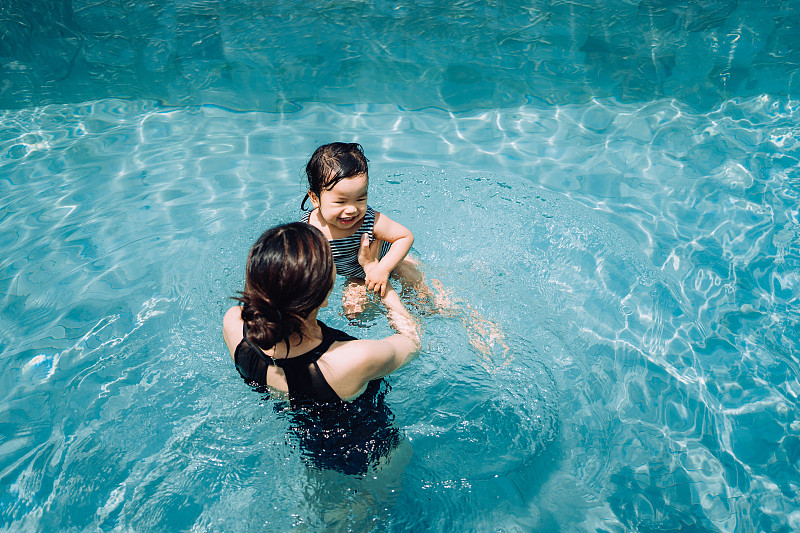 快乐的亚洲蹒跚学步的女孩享受家庭与母亲的时间，并在夏天的游泳池有乐趣图片下载