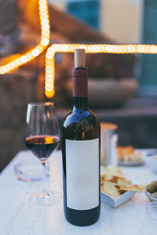 桌上放着一瓶红酒和一只玻璃杯，薯条，橄榄，餐厅里就有。柔和的色彩，夏天，意大利。为文本复制空间。意大利利古里亚省特拉罗。图片下载