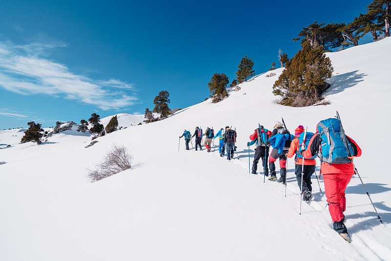冬季，高山登山队一行走到高海拔的山峰图片素材