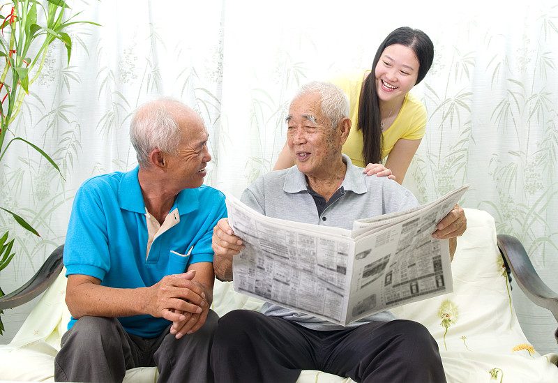 年轻女人和男人在家里看报纸图片素材