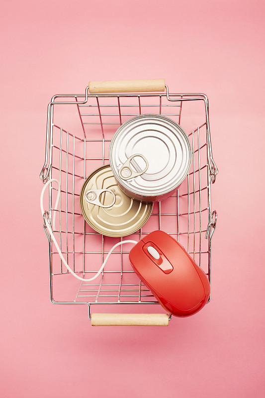 正上方拍摄的购物篮，罐头食品和红色电脑鼠标在粉红色的背景图片下载