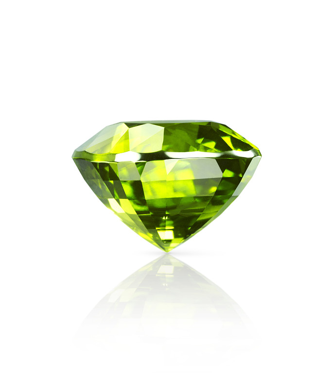 闪光的淡绿色橄榄石宝石躺在一个白色的表面上有一个下降的阴影和反射的特写侧视图图片素材