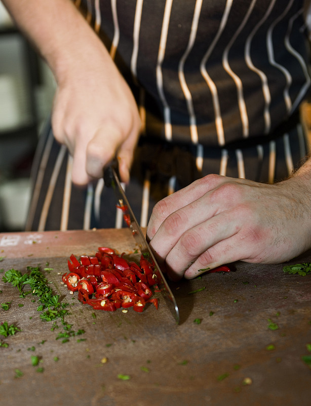 厨师在商业厨房切红辣椒的特写图片素材