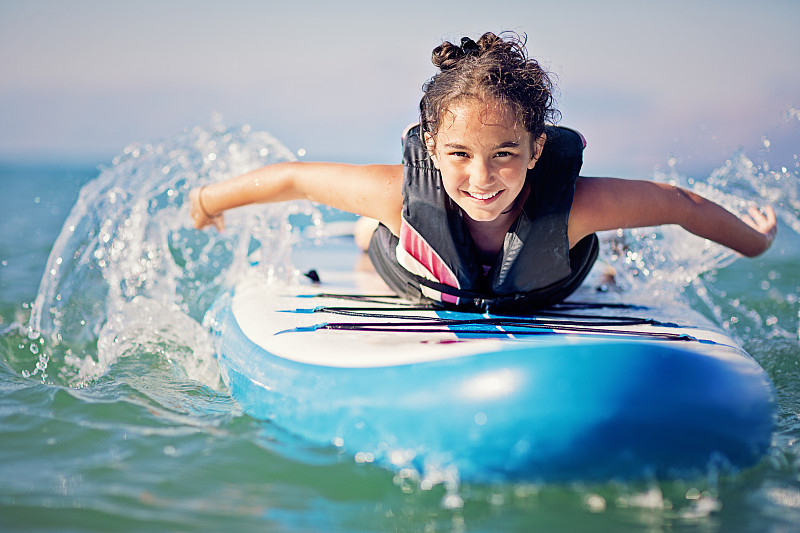 小女孩在海里划桨板上的肖像图片素材