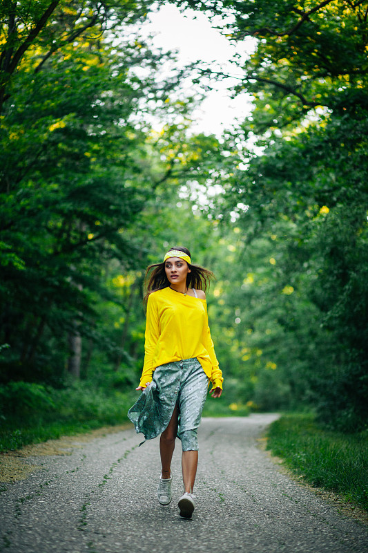 美丽的时尚女人穿着黄色在绿色的森林图片下载