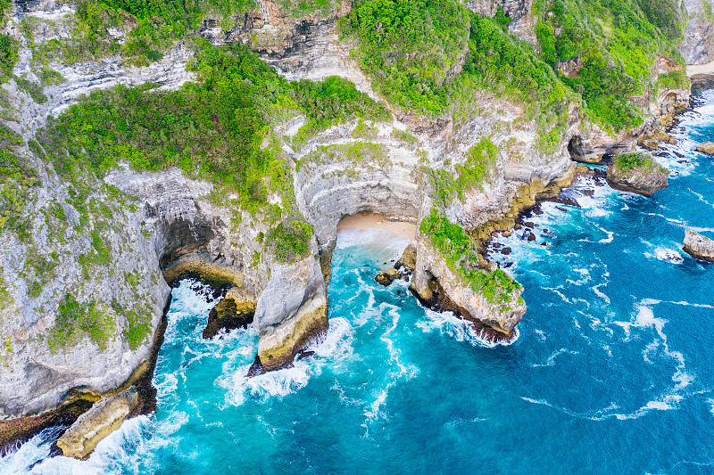 蓝色的海洋和被热带植物覆盖的悬崖。从上面看巴厘岛海岸。空中无人机拍摄。图片素材
