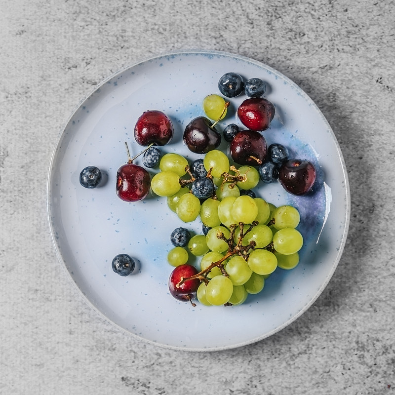 灰色背景上的各种水果(葡萄、樱桃和蓝莓)图片素材