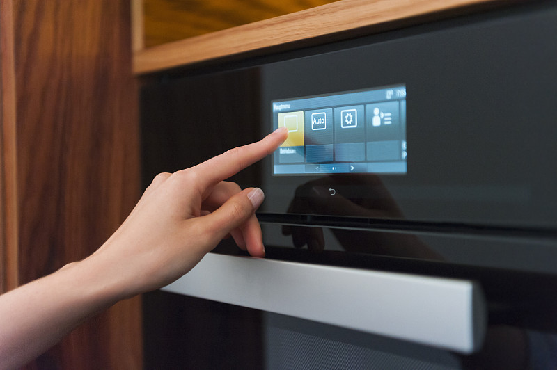 女人在厨房用手触摸烤箱的数字显示器图片下载