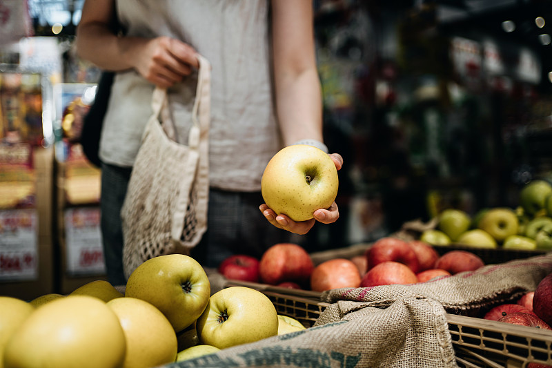 近距离拍摄年轻的亚洲妇女在农贸市场购买新鲜的有机水果与棉网环保袋。环保零浪费理念图片下载