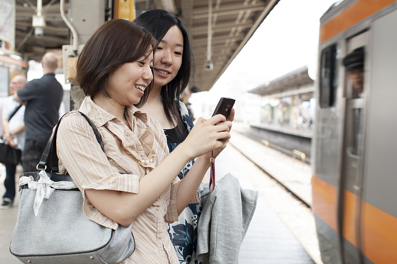两个20多岁的女孩在地铁上用手机图片素材