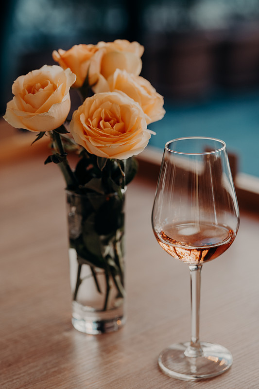 酒与玫瑰花瓶在桌子上的特写图片素材