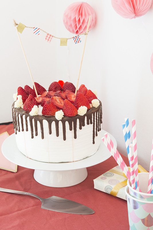 派对桌上的蛋糕有糖衣，巧克力和草莓图片素材